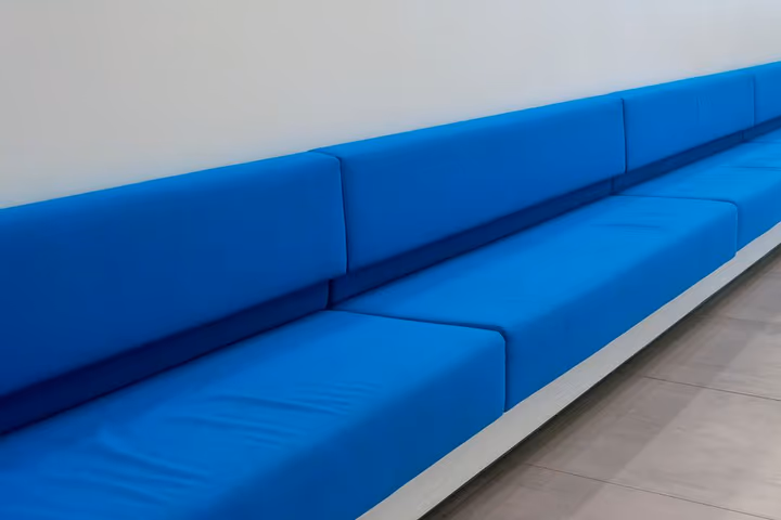 Un canapé long bleu minimaliste disposé contre un mur blanc dans une pièce moderne et épurée.